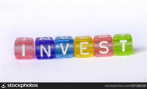 Text Invest on colorful wooden cubes over white