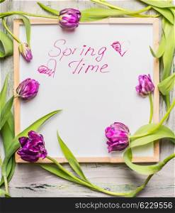 Text Springtime on white chalkboard with purple lovely Tulips flowers.
