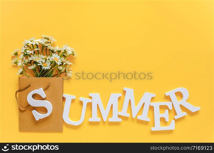 Text SUMMER from white volume letters and field chamomiles flowers in craft package on yellow background. Greeting card Flat Lay Copy space Concept Hello summer, summertime.. Text SUMMER from white volume letters and field chamomiles flowers in craft package on yellow background. Greeting card Flat Lay Copy space Concept Hello summer, summertime