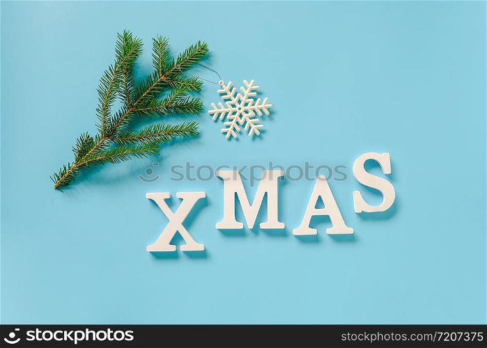Text Xmas from white letters and christmas decoration snowflake toy on spruce branch, blue background. Concept Merry christmas. Copy space Top view Flat lay Template for design, card, invitation.. Text Xmas from white letters and christmas decoration snowflake toy on spruce branch, blue background. Concept Merry christmas. Copy space Top view Flat lay Template for design, card, invitation