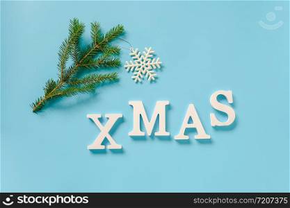 Text Xmas from white letters and christmas decoration snowflake toy on spruce branch, blue background. Concept Merry christmas. Copy space Top view Flat lay Template for design, card, invitation.. Text Xmas from white letters and christmas decoration snowflake toy on spruce branch, blue background. Concept Merry christmas. Copy space Top view Flat lay Template for design, card, invitation