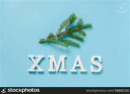 Text Xmas from white volume letters and nature green fir branch on blue background. Concept Merry christmas. Minimal style Copy space Top view Flat lay Template for design, card, invitation.. Text Xmas from white volume letters and nature green fir branch on blue background. Concept Merry christmas. Minimal style Copy space Top view Flat lay Template for design, card, invitation
