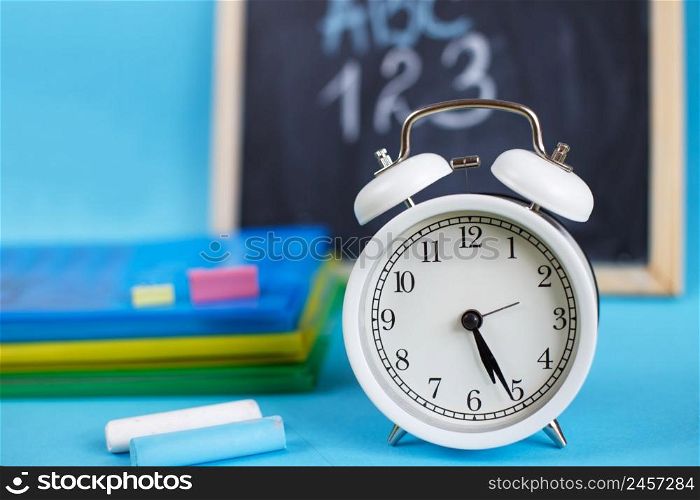 Textbooks and alarm clock on a blue background. Back to school. Library, education. Concept Education or business. Textbooks and alarm clock with school chalkboard on a blue background. Back to school. Concept Education or business