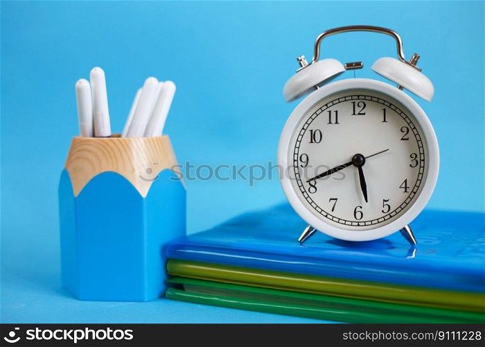 Textbooks and alarm clock on a blue background. Back to school. Library, education. Concept Education or business. Textbooks and alarm clock on a blue background. Back to school. Concept Education or business