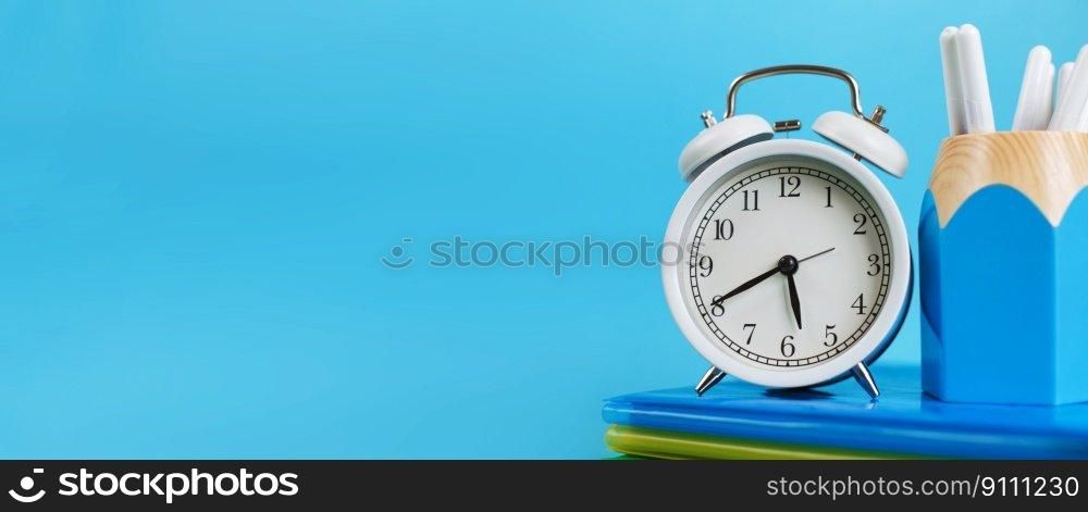 Textbooks and alarm clock on a blue background. Back to school. Library, education. Concept Education or busi≠ss. ban≠r. Textbooks and alarm clock on a blue background. Back to school. Concept Education or busi≠ss. ban≠r
