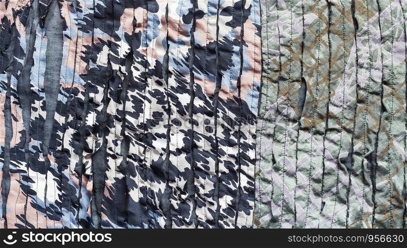 textile panoramic background - spotted ornament of scarf stitched from fabric with cuts