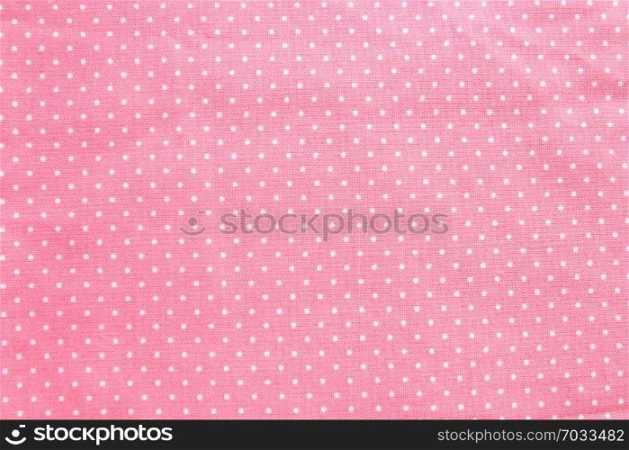 Texture and background of pink cotton fabric with small white polka dots.