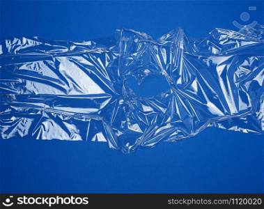 texture of a transparent stretching plastic film for packaging products on a blue background, full frame, close up