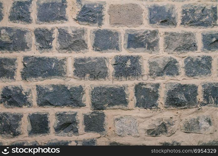 Texture of black basalt brick wall.