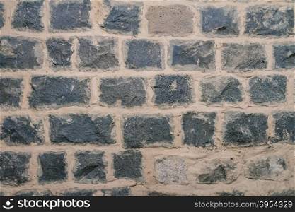 Texture of black basalt brick wall.