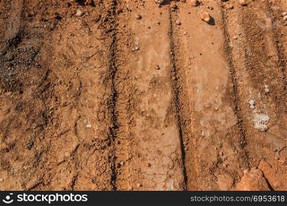 Texture of brown dirt with tractor tyre tracks.