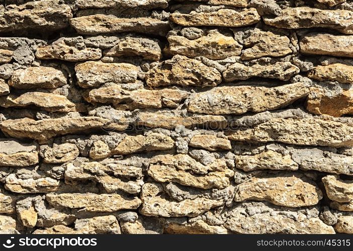 Texture of brown stone coquina wall with cement mortar