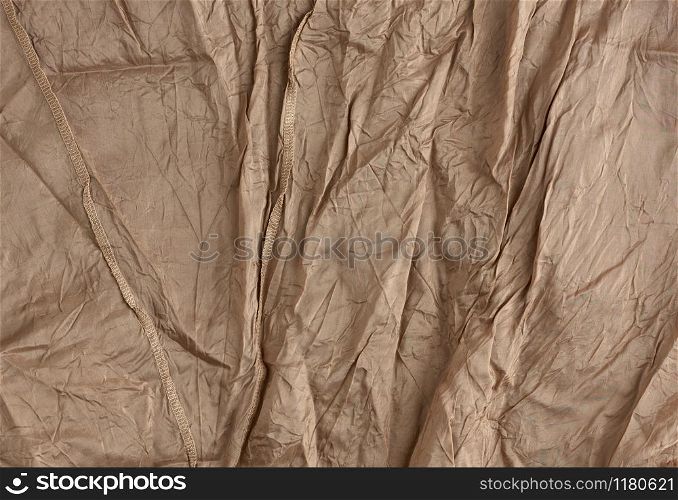 texture of crumpled brown synthetic fabric with seams for sewing clothes, full frame