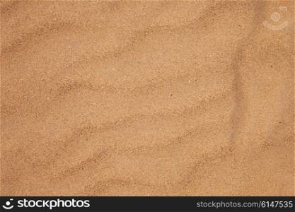 Texture of dry beach sand with wavy patterns closeup