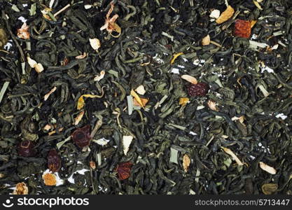 Texture of dry green tea with petals of flower and fruit close up