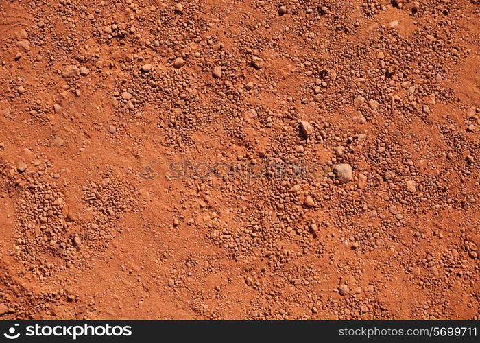 Texture of dry red clay with stones close-up