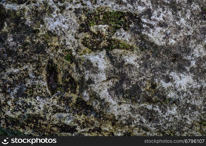 Texture of gray mountain rock surface with moss