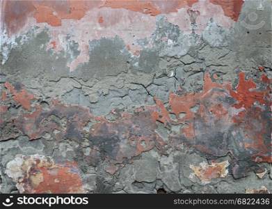 Texture of old damaged plaster wall with peeling red paint