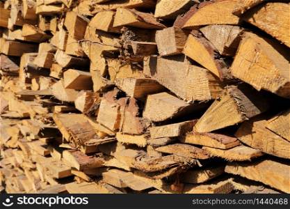 texture of pine firewood. Chipped firewood is on the heap. Woodpile of firewood close-up. A stack of dry firewood, visible texture and cracks in the tree. selective focus. texture of pine firewood. Chipped firewood is on the heap. Woodpile of firewood close-up. A stack of dry firewood, visible texture and cracks in the tree. selective focus.