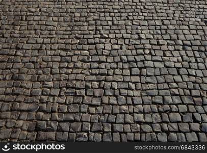 Texture of square black cobblestone pavement surface