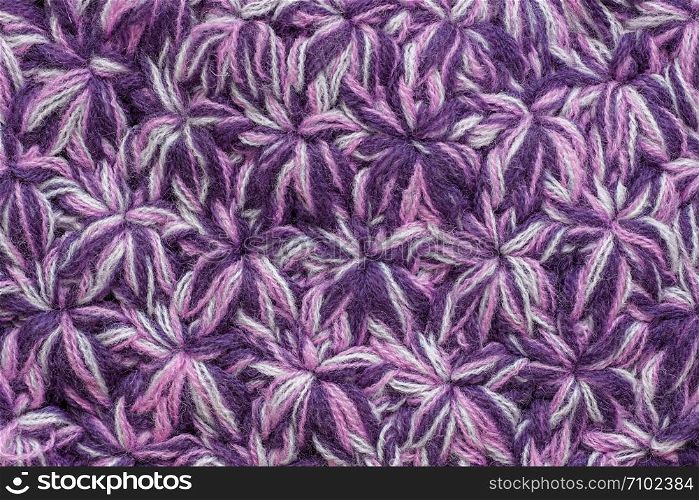 Texture of the knitted fabric. Crochet from yarn, handmade. A pattern asterisks or snowflakes of color yarn.