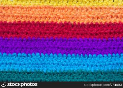 Texture of the knitted fabric. Crochet from yarn, handmade. Horizontal stripes of rainbow colors.