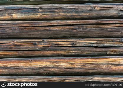 Texture of the walls of the old log house in bright sunlight.
