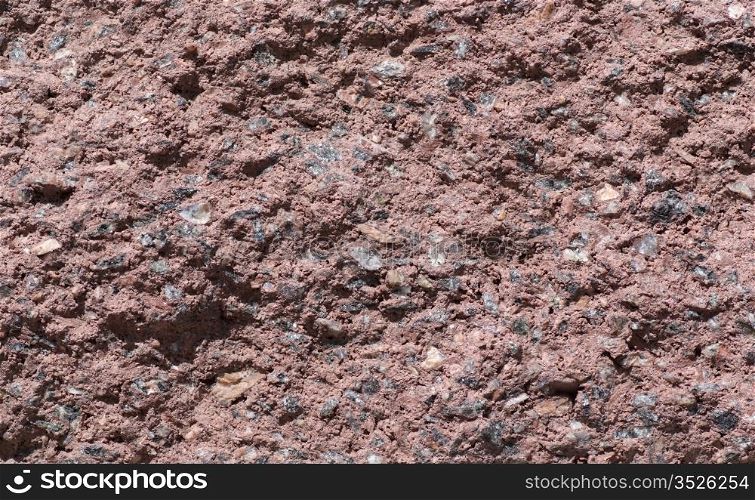 Texture of wall made of small pieces of granite and stone. It have slightly brown tint.