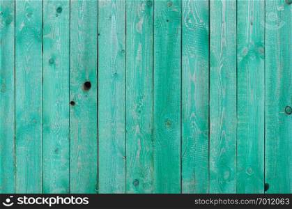 Texture of weathered green painted wooden fence with knot holes