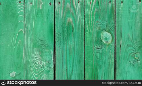 Texture of weathered wooden green painted fence, close-up vintage background