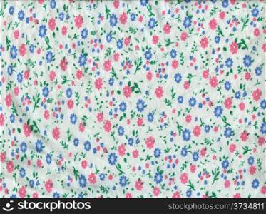 Texture of white knitted fabric in small pink and blue flowers