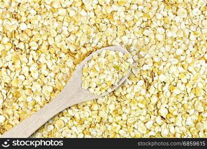 Texture of yellow pea flakes with a wooden spoon