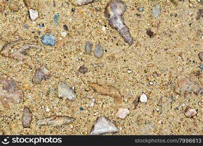 Texture of yellow sand and pebbles of colored granite