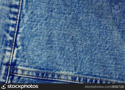 Textured vintage background - blue jeans textile denim with seam of fashion design in close-up (high details).