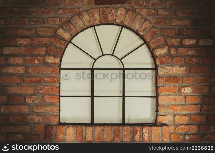Textures and close up detailed patterns concept. Big rounded window on red brick wall. Big rounded window on red brick wall