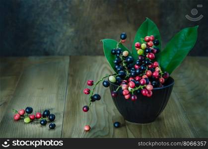 Thai Blueberry in black bowl over wooden background , still life