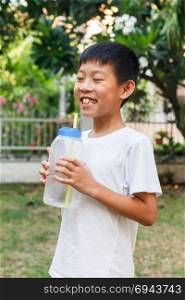 Thai boy drink cold water from plasctic bottle using straw.