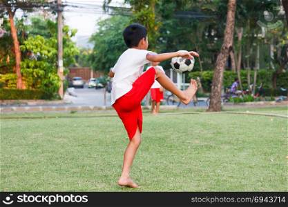 Thai boy playing soccer in garden.