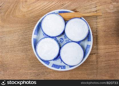 Thai Coconut Milk Custard is a thai dessert made from rice flour, coconut milk and sugar put the small ceramic cups place are on a wooden floor. Khanom Thuai,