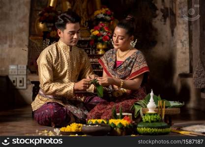 Thai couple in traditional dress costume making and decorating Krathong. Loy Krathong Festival.
