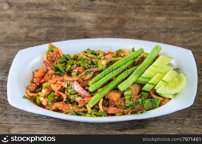 Thai cuisine spicy pork salad on wooden