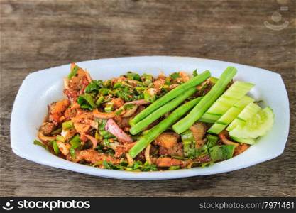 Thai cuisine spicy pork salad on wooden