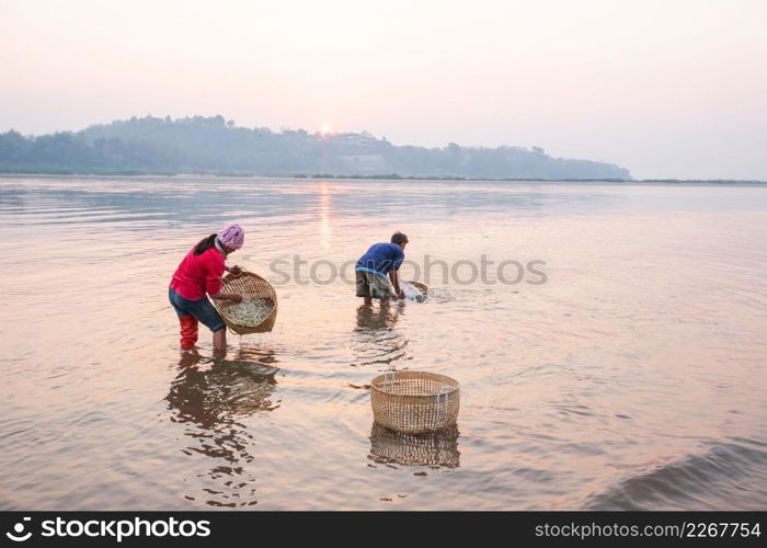 Thai farmer washing Bean Sprouts in Mekong River at sunrise. Bean Sprouts in bamboo basket. Organic vegetables. Thai-Laos border background. Chiang Khong District, Chiang Rai, Thailand. Simple life.