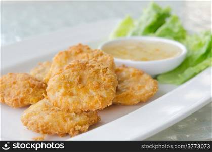 Thai Food Fried Fish Cake (Tod Mun Pla) served with sweet sauce and fresh lettuce. fish cakes