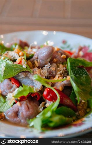 Thai food on dinner table, spicy beef salad with green celery leaves in vintage caremic plate