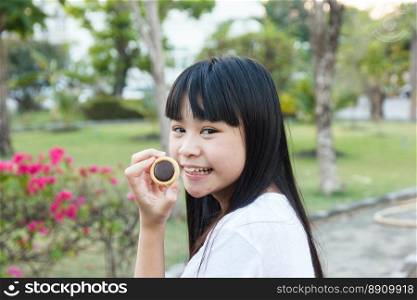 Thai girl eating chocolate cookie at garden.