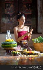 Thai girl in traditional dress costume making and decorating Krathong. Loy Krathong Festival.