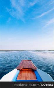 Thai long tail boat front bow in peaceful Nong Harn lake, Udonthani - Thailand. Wooden boat under beautiful blue morning sky over red lotus lake.