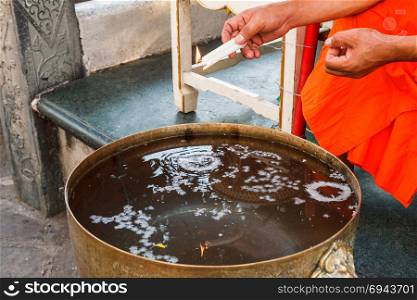 Thai monk making holy water with candle.
