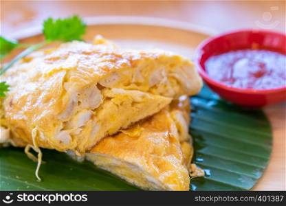 Thai Omelette with crab, fried egg with crab meat, thai famous street food and restaurant cuisine on wooden table.